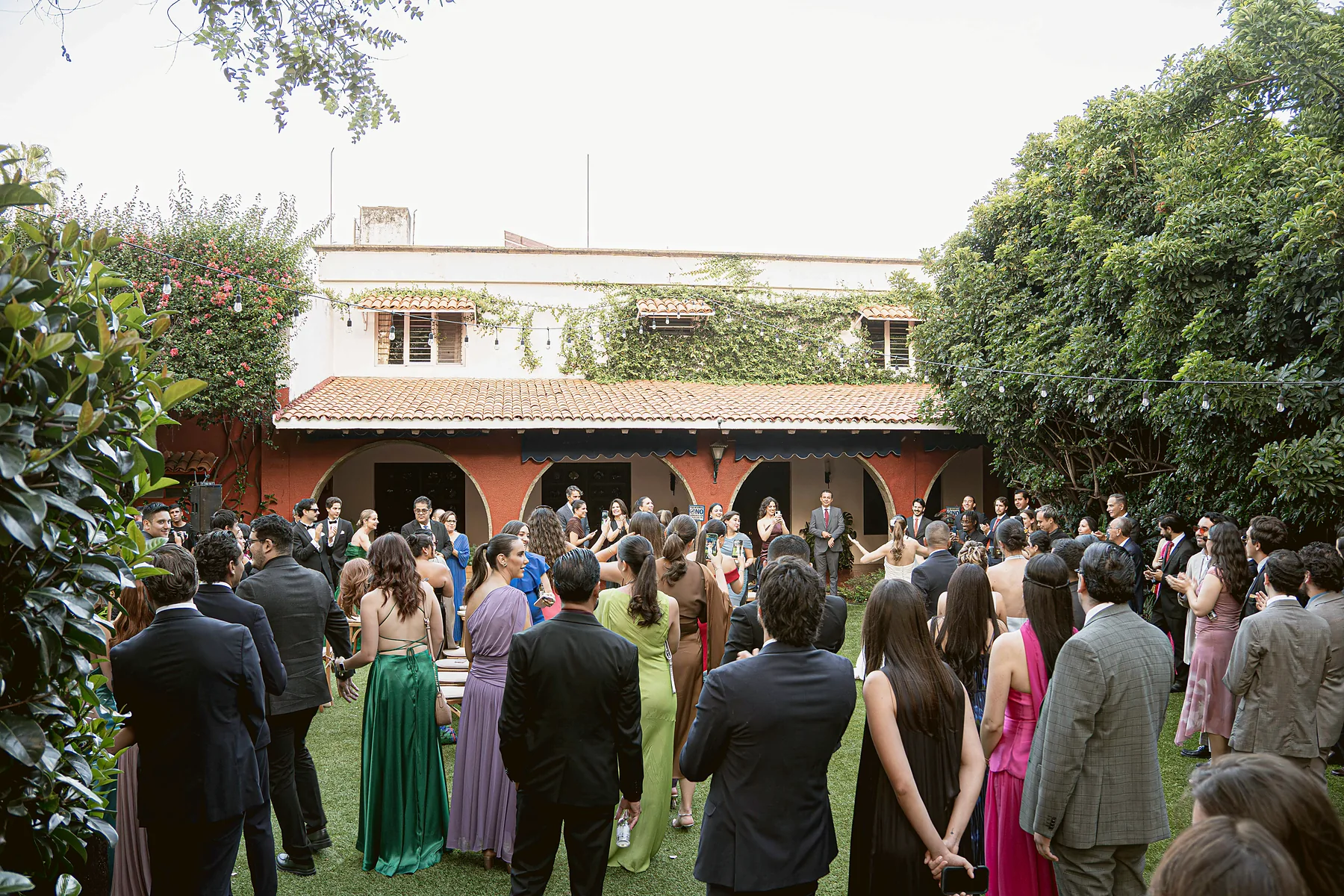 Ceremonia frente a la arquería de la casona, con los invitados de pie sobre el jardín