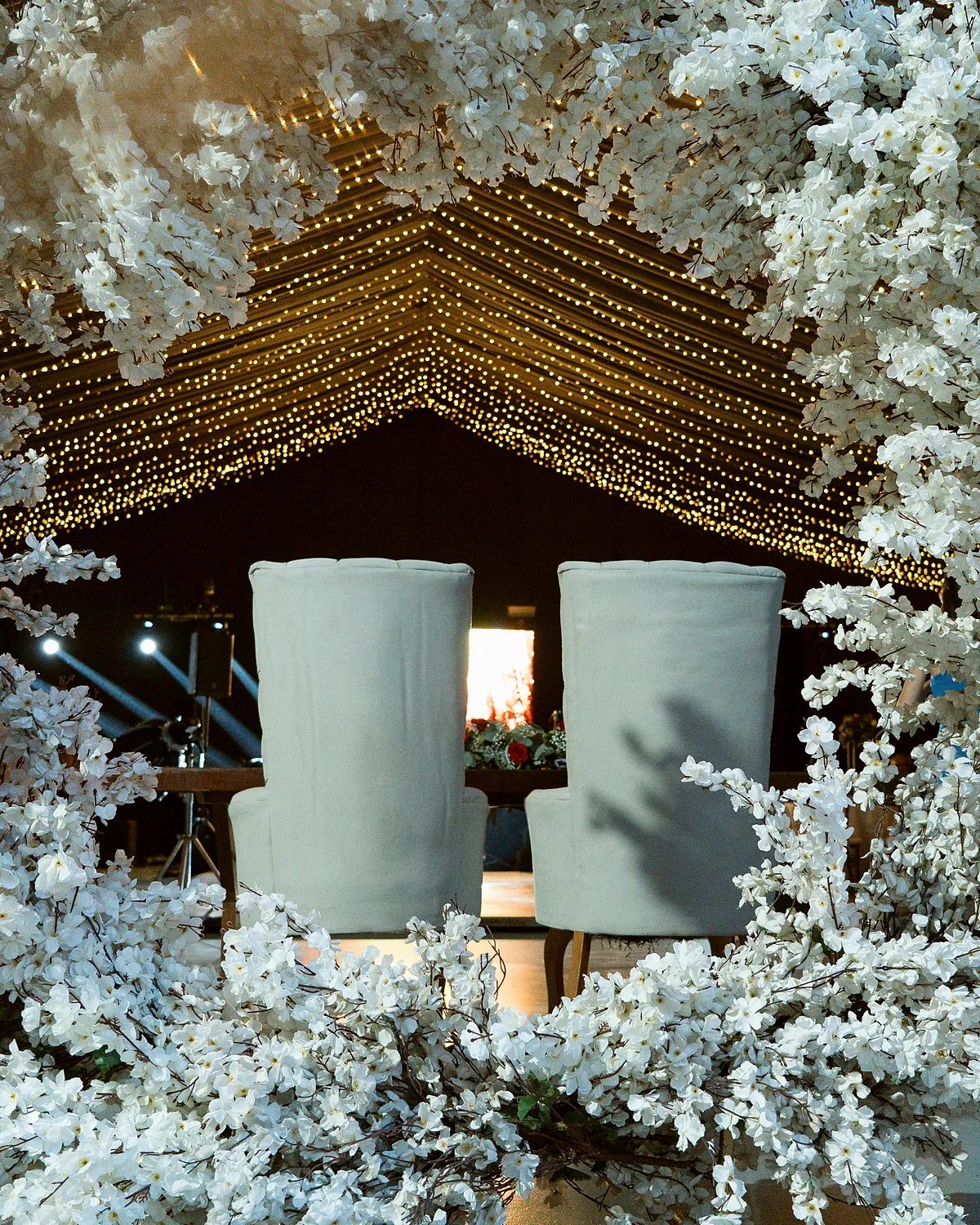 Los dos sillones de la ceremonia, enmarcados en flor blanca bajo el plafón de luces